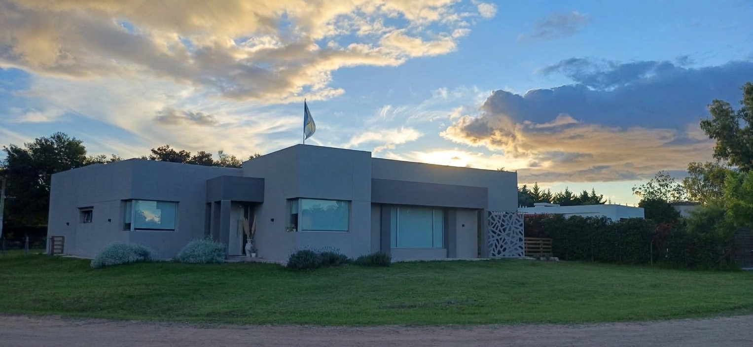 Casa moderna de una planta con revestimiento gris al atardecer